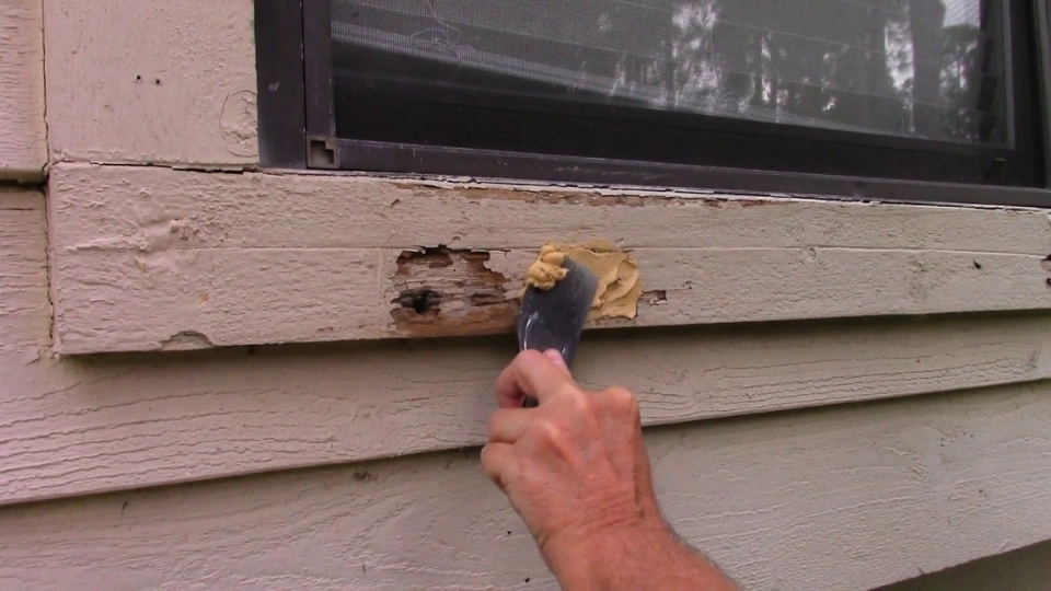 A technician injecting specialized epoxy into a structural joint of a wooden window frame to repair wood rot in Florida.