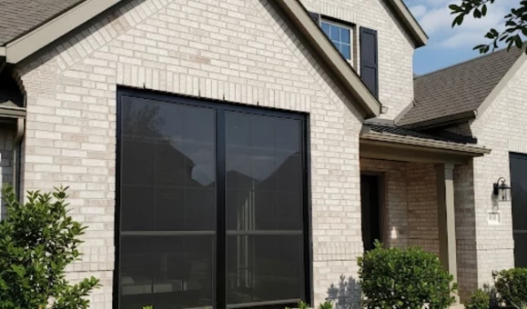 A sleek, dark solar screen installed on a sun-facing window in a Benbrook home, demonstrating our energy-efficient solutions.